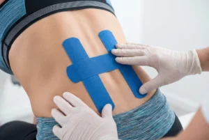 Hombre aplicando cinta kinesiológica para el dolor de espalda utilizando la técnica del patrón en H para soporte lumbar