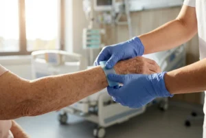 Personal de enfermería aplicando cinta de gel de silicona en el brazo de un paciente de edad avanzada, demostrando una adhesión suave y capacidad de reposicionamiento