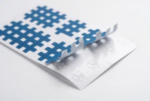 Individuelles Trägerpapier für Cross-Tape mit hochwertigem blauem Gitter-Kinesiologie-Tape, teilweise abgezogen, zeigt elegantes gedrucktes Branding