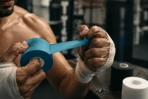 Sporttape mit Zackenrand, das von einem Boxer in einer echten Studio-Umgebung sauber abgerissen wird