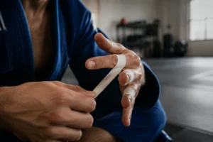 BJJ athlete wrapping fingers with narrow sports tape, showcasing premium athletic tape customization options for martial arts brands.